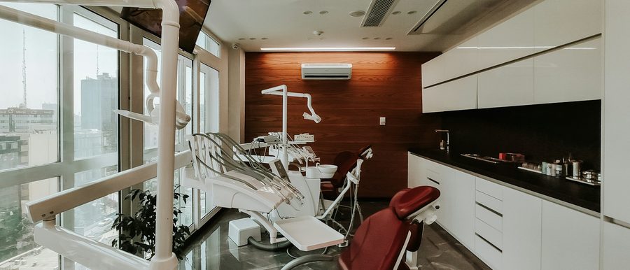Behandlungsraum des Dentalstudios mit Fensterfront und dunkler Holzwand