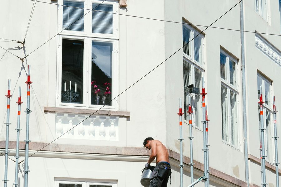 Maler auf dem Geruest bei Fassadenarbeiten