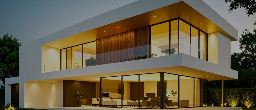 Modernes Wohnhaus mit beleuchteter Glasfront in der Abenddämmerung